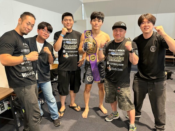 KMMA 웰터급 및 슈퍼라이트급 타이틀 도전자 출신 문홍범이 2025년 8월 일본 효고현 아마가사키시 주쇼키고센터에서 소속 체육관 신MMA 관계자들과 ACF 라이트급 챔피언 등극 기념 촬영을 하고 있다. 사진 | 스탠다드앤드프로그레스 스포츠에이전시